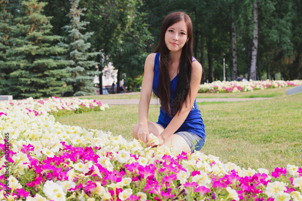 Pretty girl sits near the flowerbeds Pretty girl sits near the flowerbeds
