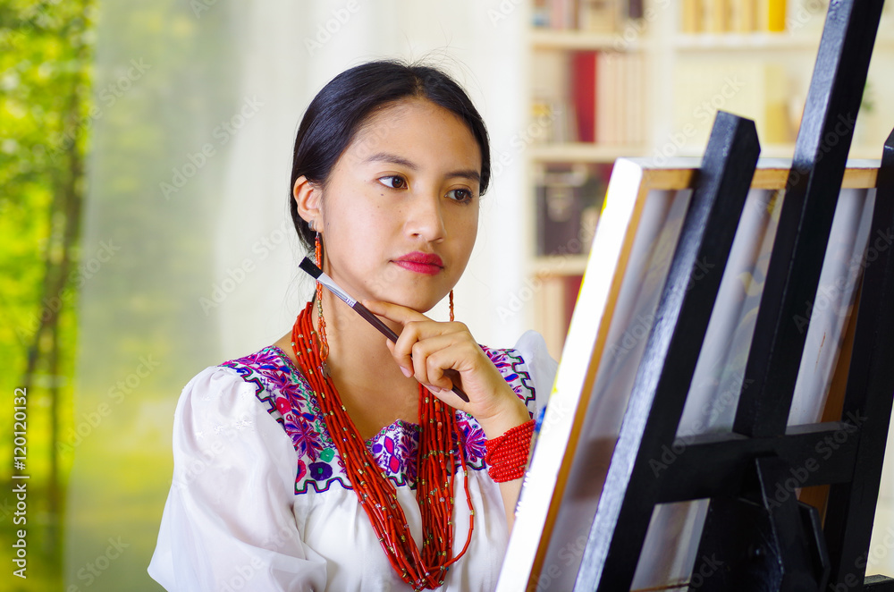 Φωτογραφία Young brunette woman wearing traditional andean clothing painting on canvas insi