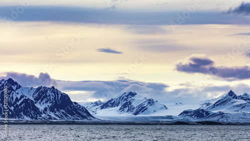 Clouds over snowy mountains and glacier in the arctic photo