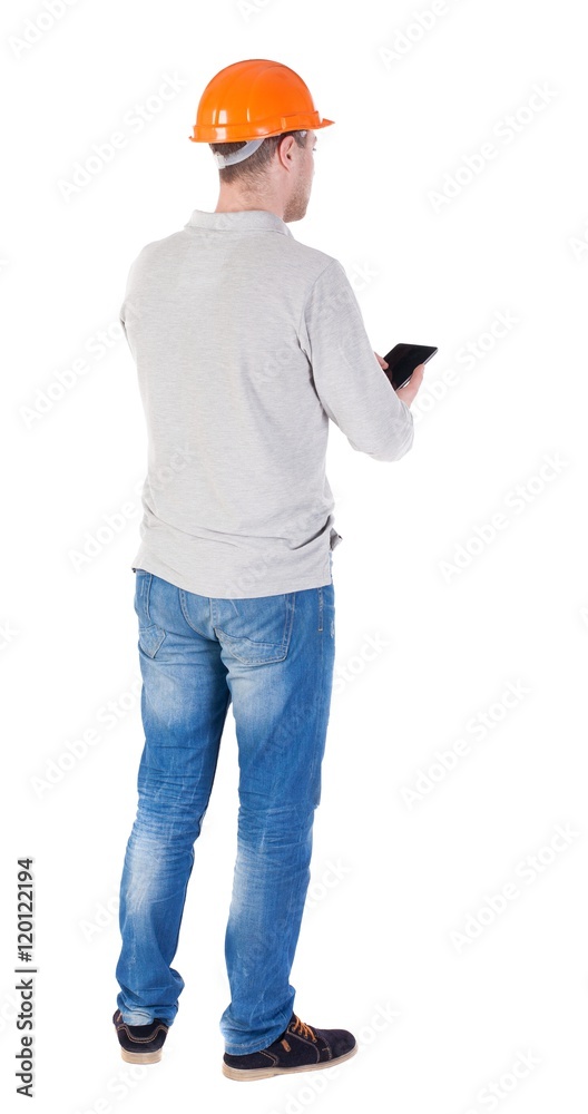 young engineer in a protective helmet with tablet computer in the hands of. Rear view people collection. backside view of person. Isolated over white background. Engineer verifies the work done with young engineer in a protective helmet with tablet computer in the hands of. Rear view people collection. backside view of person. Isolated over white background. Engineer verifies the work done with