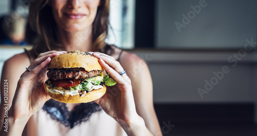 Young girl holding in female hands fast food burger, american unhealthy calories meal on background, mockup with copy space for text message or design, hungry human with grilled hamburger front view