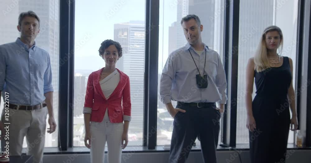 Multi-ethnic team of four business people, men and women, stand in front of windows in open-plan city office, in Downtown Los Angeles. Medium long shot, recorded hand held in slow motion at 60fps Multi-ethnic team of four business people, men and women, stand in front of windows in open-plan city office, in Downtown Los Angeles. Medium long shot, recorded hand held in slow motion at 60fps