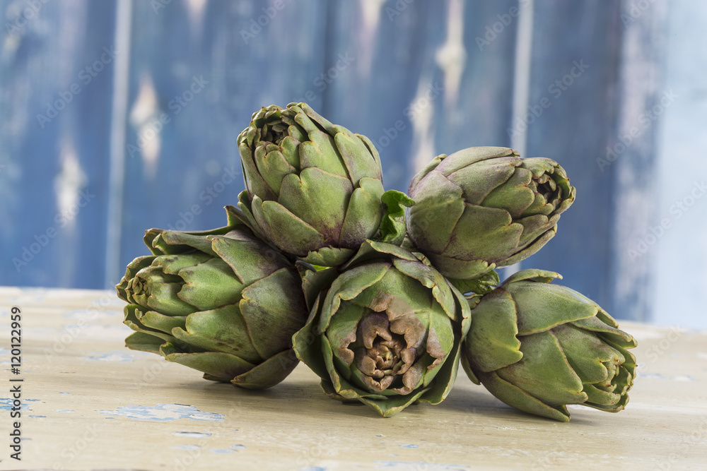 Fototapeta premium Ripe green artichokes isolated on blue background