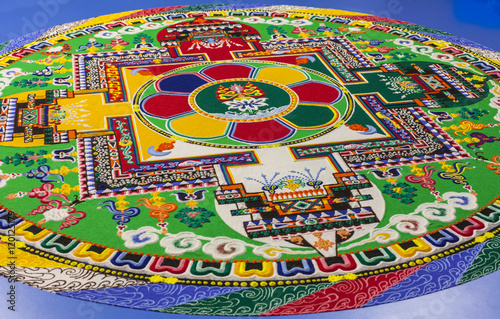 Sand Buddhist mandala on blue background close up