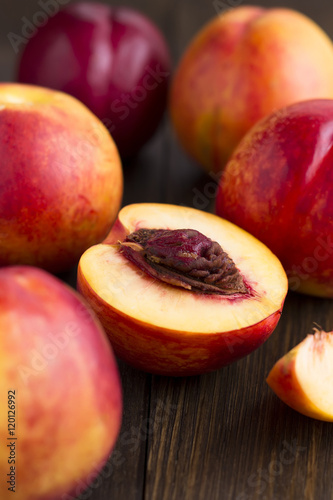Sweet ripe whole nectarines and half on the wooden table.