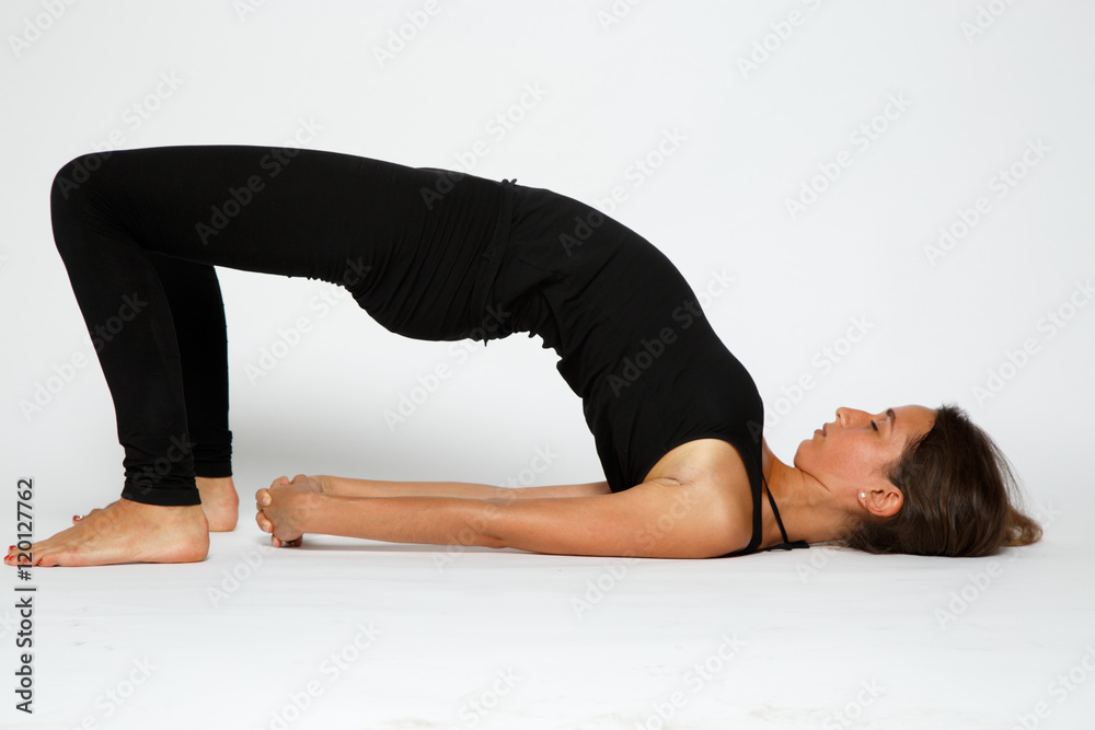 Girl makes yoga exercise on the white background in black Girl makes yoga exercise on the white background in black