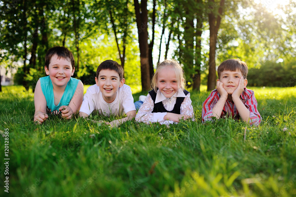 four children lie on their stomachs on the grass and smiling four children lie on their stomachs on the grass and smiling