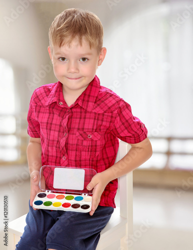 The boy draws paints