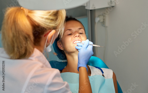 Close up of Female dentist treats patients teeth in the dentist chair at dental clinic.Medicine, health, stomatology concept/Beautiful woman dentist treating a patient's teeth in dental office