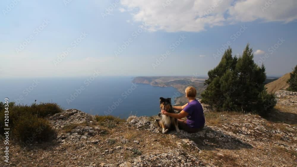 An elderly woman is resting on top of a mountain vacation with his funny big dog An elderly woman is resting on top of a mountain vacation with his funny big dog