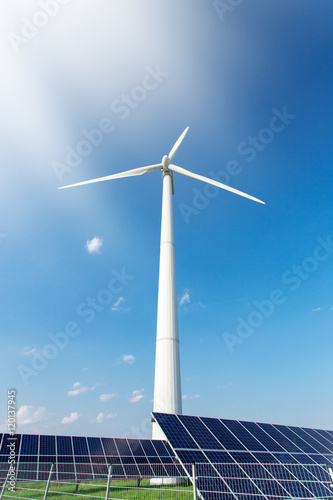 Windmill and solar panels on blue sky at daytime