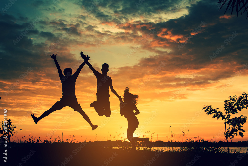 The silhouette of three people jumping with sunset background The silhouette of three people jumping with sunset background