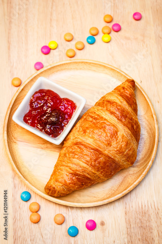 Tasty croissants with jam on wooden background.