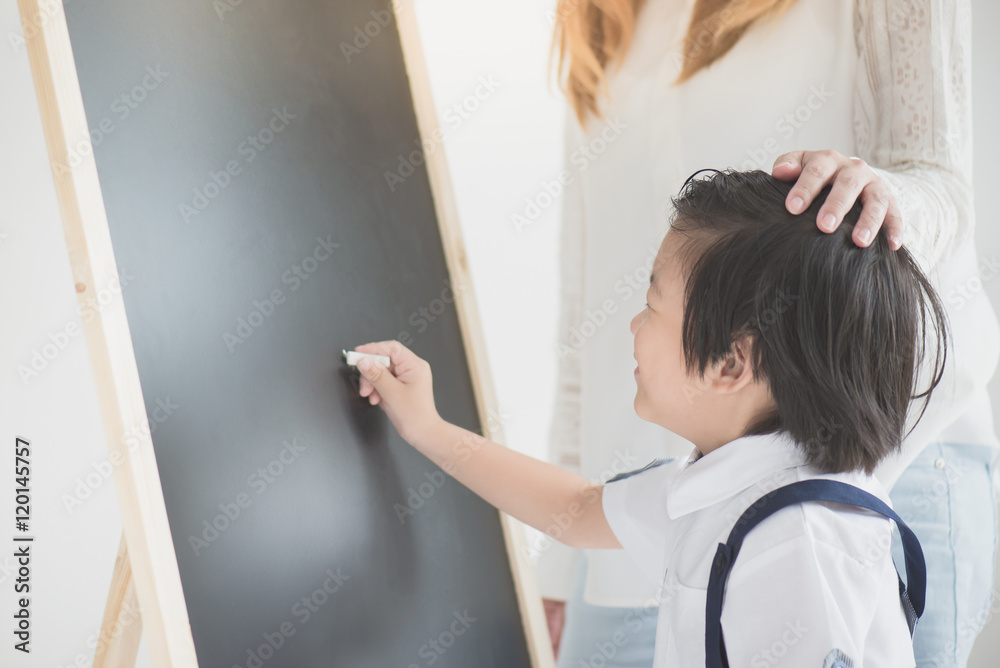 Cute Asian child writing on blackboard with Cute Asian child writing on blackboard with