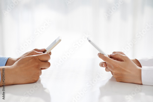 Hands of people text messaging with each other