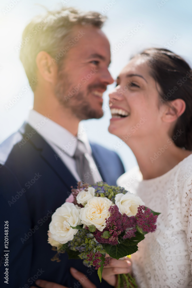  Portrait of smiling newlyweds, focus on the bride's bouquet