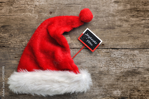chapeau de Noël avec petit panneau "joyeuses fêtes" sur fond bois
