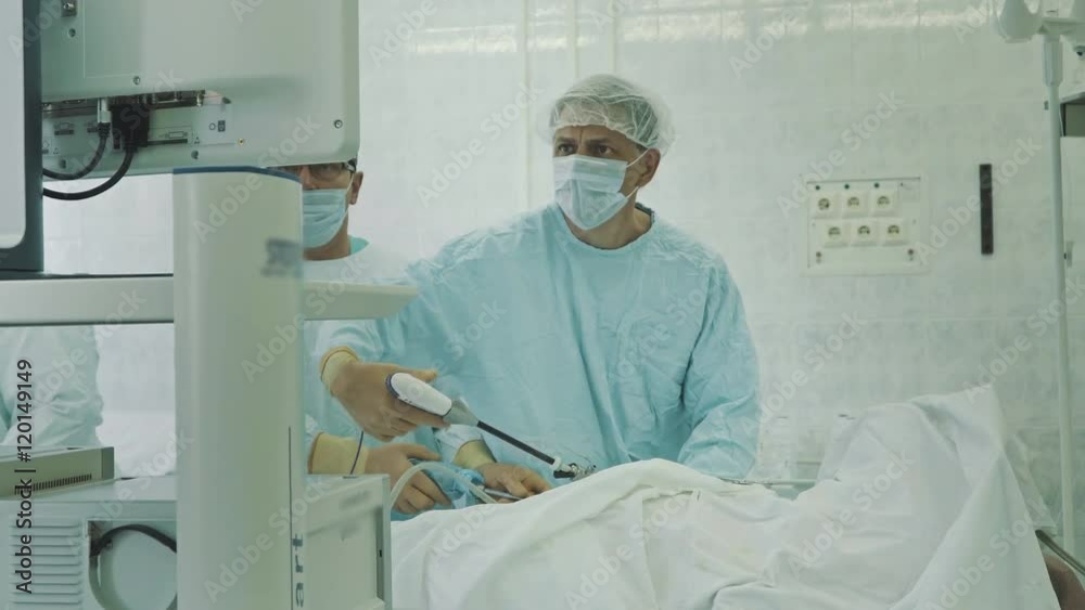Laparoscopic Surgeons team performing real operation in operating room. Surgeon operating patient, knee replacement nurse adding tools surgeon, surgical instruments, holding hands Laparoscopic Surgeons team performing real operation in operating room. Surgeon operating patient, knee replacement nurse adding tools surgeon, surgical instruments, holding hands