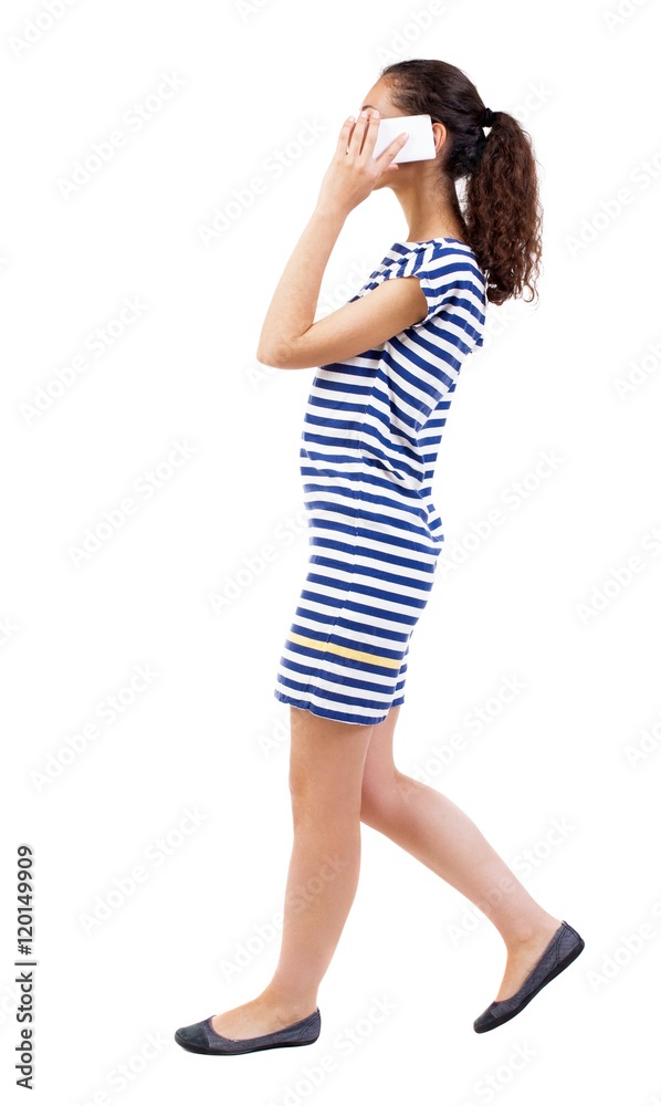 a side view of a woman walking with a mobile phone. beautiful curly girl in motion. backside view of person. Rear view people collection. Isolated over white background. African-American woman in a a side view of a woman walking with a mobile phone. beautiful curly girl in motion. backside view of person. Rear view people collection. Isolated over white background. African-American woman in a