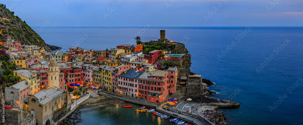 Night view from hill of Vernazza houses with lit light and blue sea, one of Cinque Terre villages , Liguria, Italy
