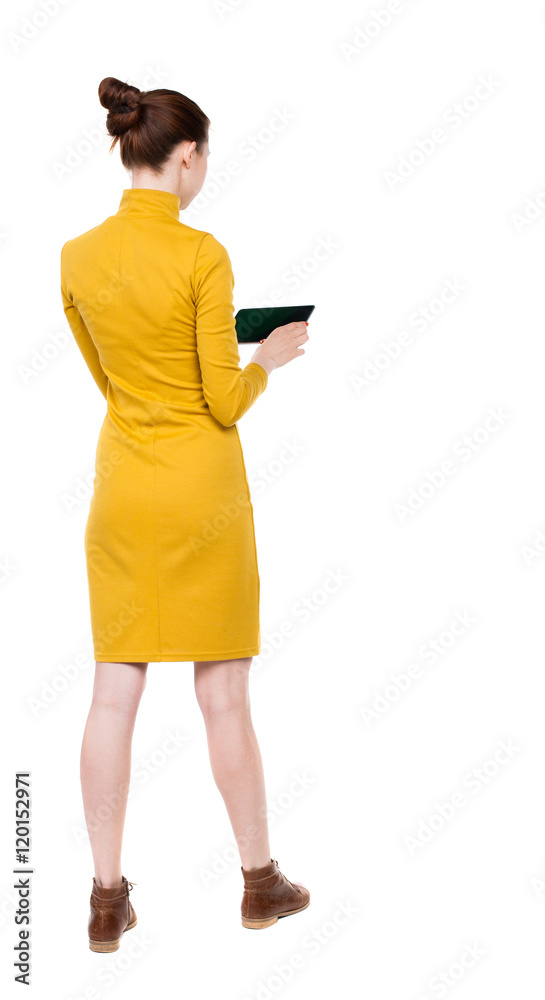 back view of standing young beautiful  girl with tablet computer in the hands of. girl  watching. Rear view people collection.  backside view of person.  Isolated over white background.