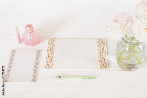 Chrysanthemum in vase, perfume, lipstick, pen, paper for notes on white background. Casual creative lady home office. Product presentation or introducing.