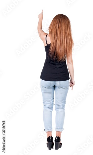 Back view of pointing woman. beautiful redhead girl in jeans. Rear view people collection. backside view of person. Isolated over white background.
