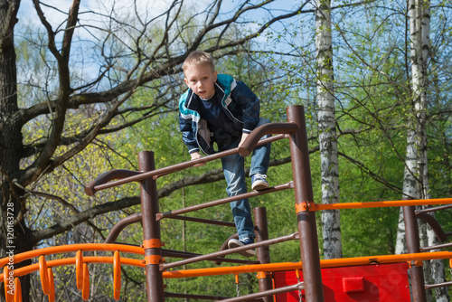 Fototapeta Naklejka Na Ścianę i Meble -  The boy climbed the ladder on the playground