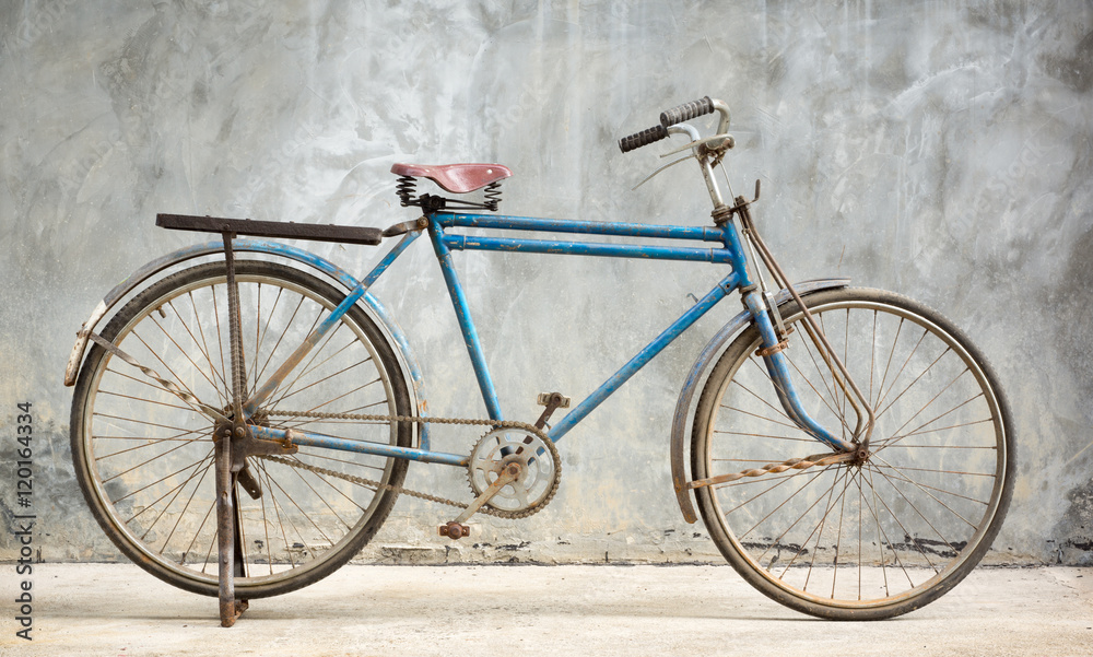 Old and rusty bicycle with grunge cement plaster wall background