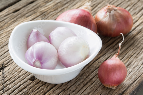 red onion and peeled in white ceramic cup on old wood