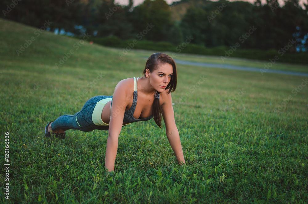 Young attractive woman training in the park. Exercise plank. Fit Young attractive woman training in the park. Exercise plank. Fit