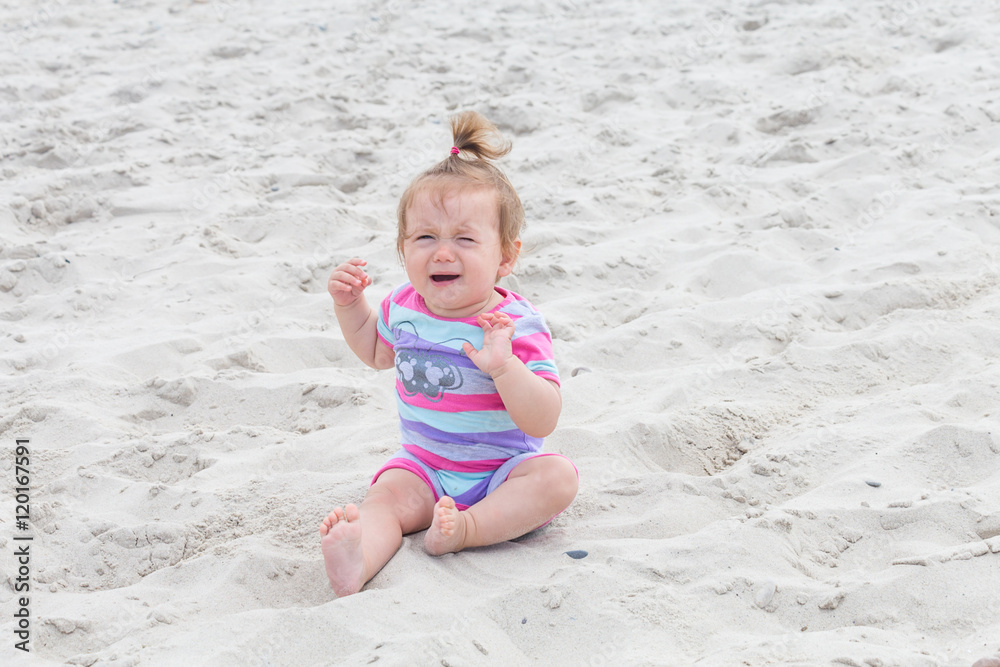 Crying baby girl,lonely cute baby girl sitting and crying in the sand Crying baby girl,lonely cute baby girl sitting and crying in the sand