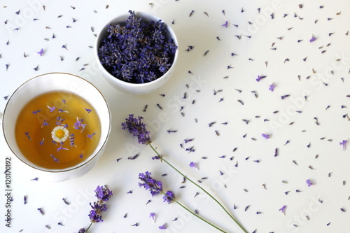 Top view of a cup of herbal tea garnished with fresh and dried lavender and camomile flowers on white background. Cup of tea drink decorated with lavandula and chamomile herbs. Photo from above. photo