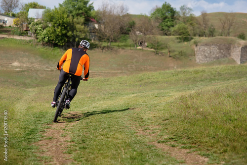 Fototapeta Naklejka Na Ścianę i Meble -  Young man traveler riding on bicycle with red backpack