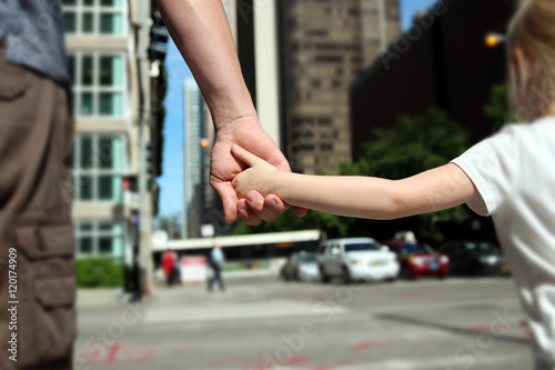 father holding  the daughter  child  hand  behind  the traffic l