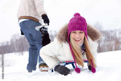 Konstfotografi Young woman lying on sled behind her boyfriend