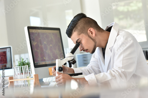 Student in biology using microscope in training class