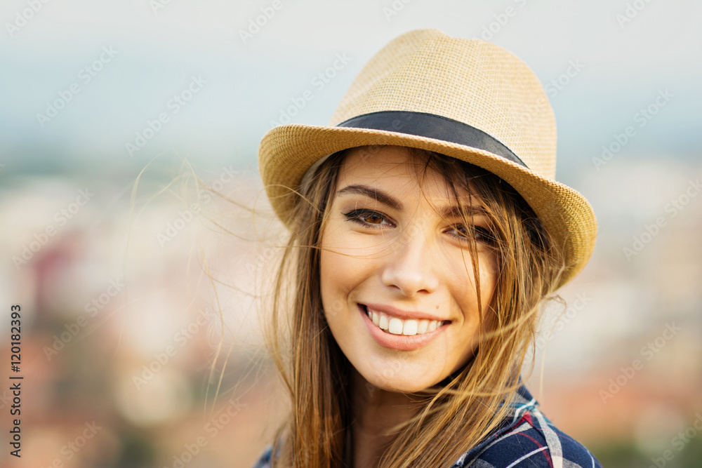 Closeup portrait of beautiful young blonde woman in brown fedora on windy autumn day