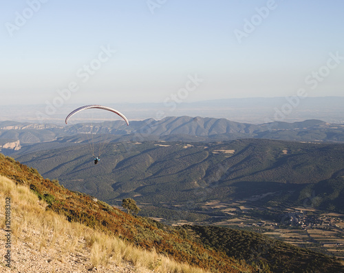 Paraglider holding ropes of orange flying wing in the air