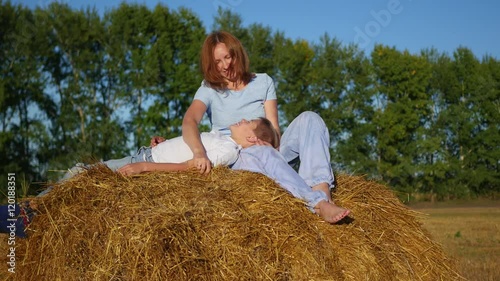 a girl with a child resting on a haystack