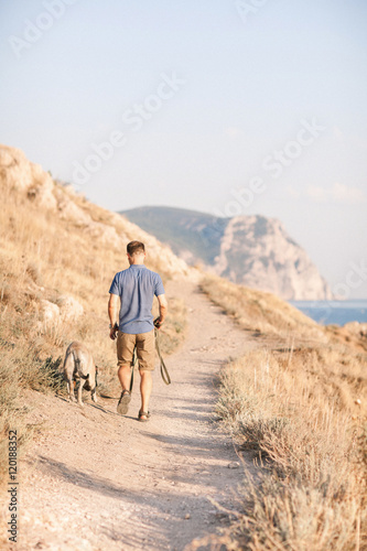 Young caucasian male walking with dog during sunrise