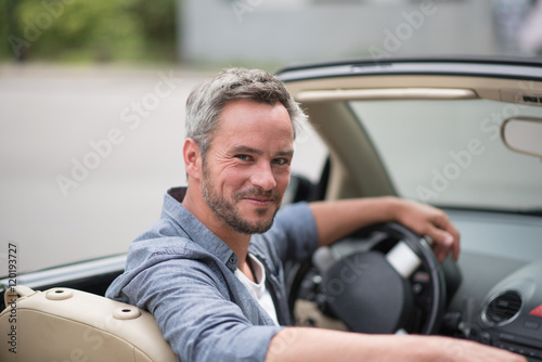  Looking at camera, handsome man driving her convertible car