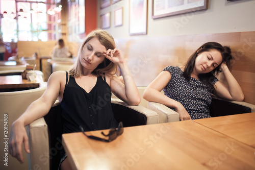 two tired females sitting in cafe and resting;