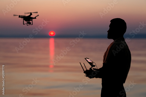 Man flying a drone near seaside at the sunset. © volff