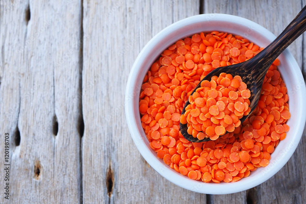Top view of peeled split red lentils in a bowl and wooden spoon.
Top view of peeled split red lentils in a bowl and wooden spoon.