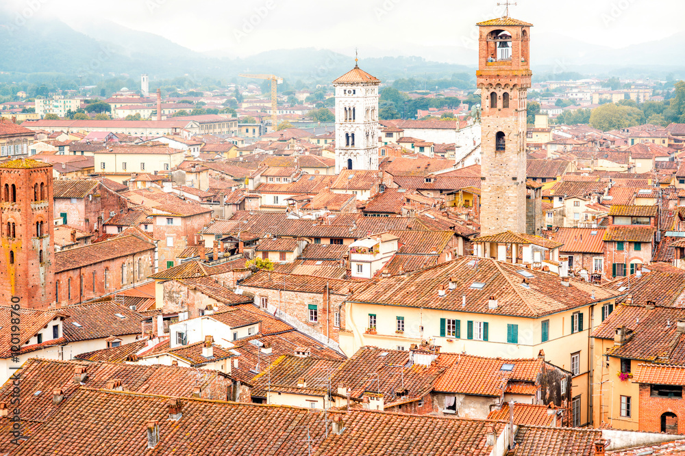 Aerial cityscape view on the old town of Lucca with bell tower San Michele basilica at the foggy weather in Italy