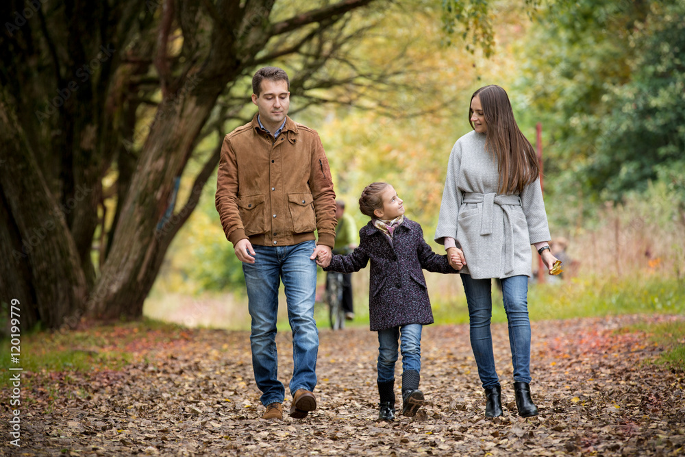 Lovely family walking in the autumn forest. Happy parents enjoying fresh air and beautiful nature, holding hands, talking, smiling and laughing. Healthy lifestyle Lovely family walking in the autumn forest. Happy parents enjoying fresh air and beautiful nature, holding hands, talking, smiling and laughing. Healthy lifestyle