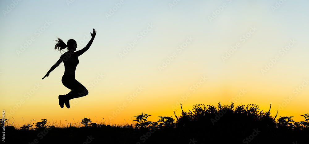 Happiness - happy jumping female silhouette at sunset Happiness - happy jumping female silhouette at sunset