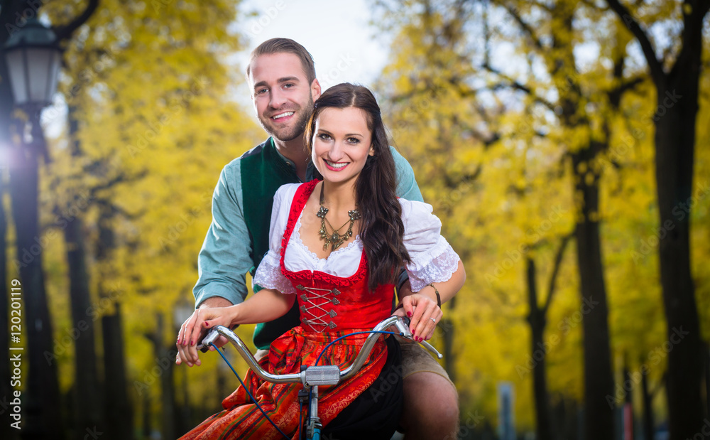 Φωτογραφία Mann und Frau in süddeutscher Tracht fahren auf Fahrrad und lachen