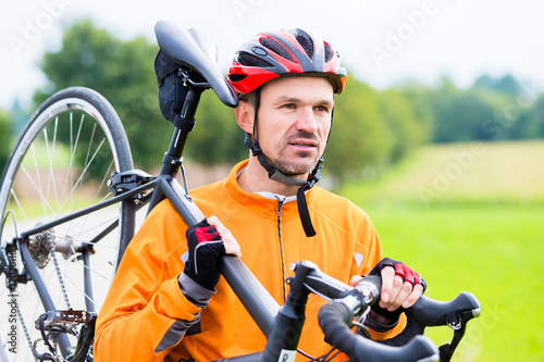 Cyclist carrying his bike over shoulder